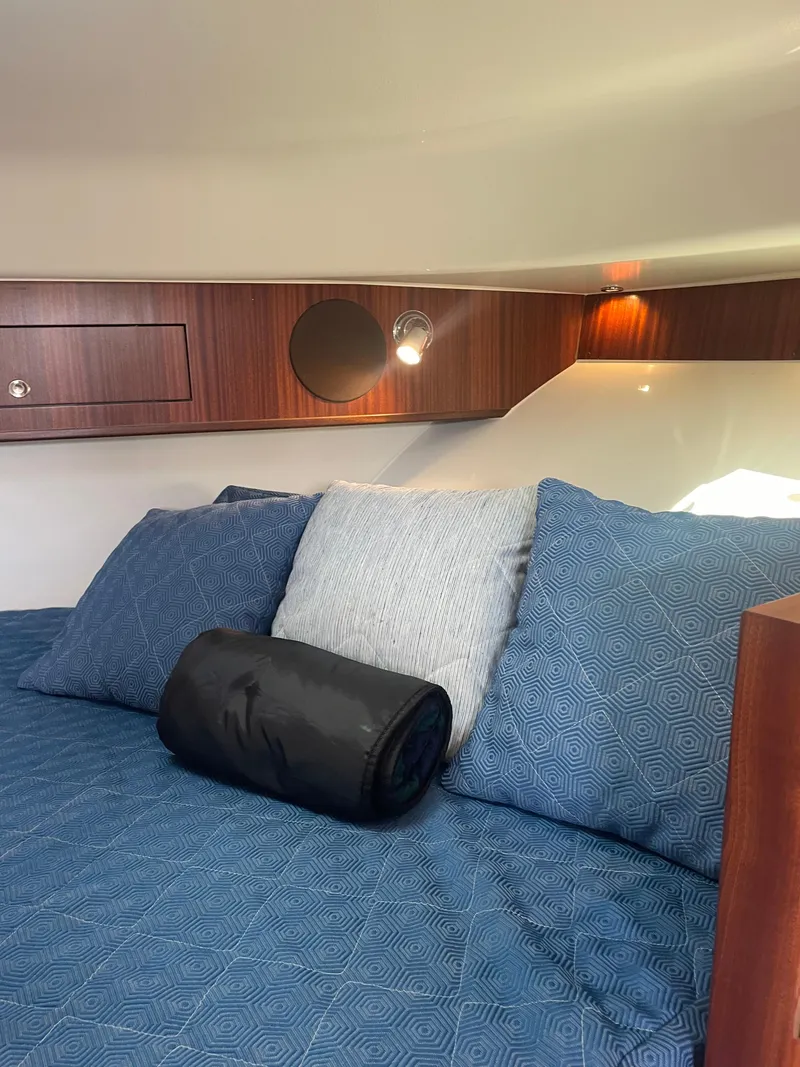 Slide: The Image of 2020 Pursuit 385 Offshore cabin interior with blue bedding and wooden accents. - 28
