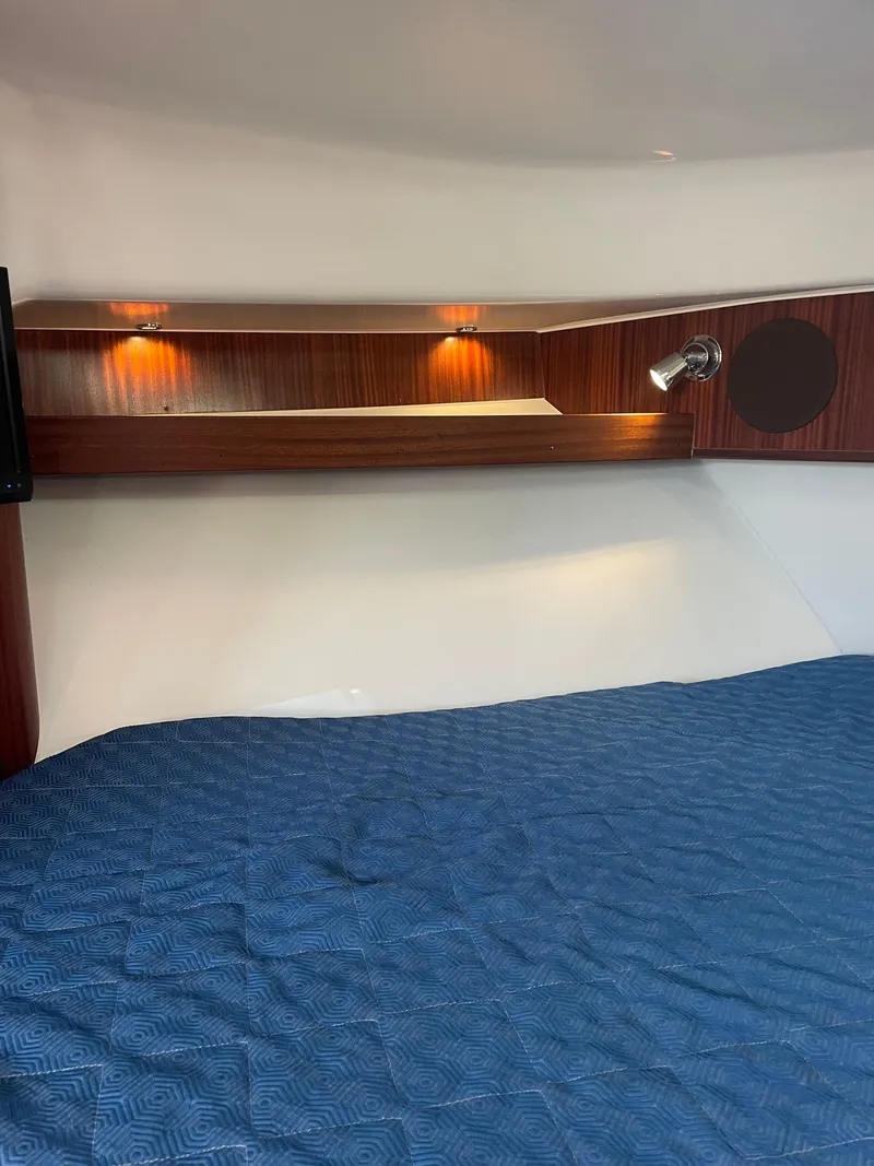 Slide: The Image of 2020 Pursuit 385 Offshore cabin interior with blue bedding and wooden accents. - 29