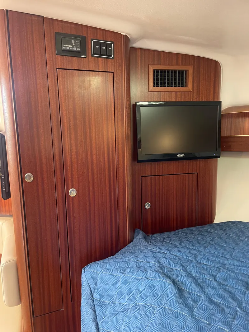 Slide: The Image of 2020 Pursuit 385 Offshore cabin interior with wood paneling and TV. - 30
