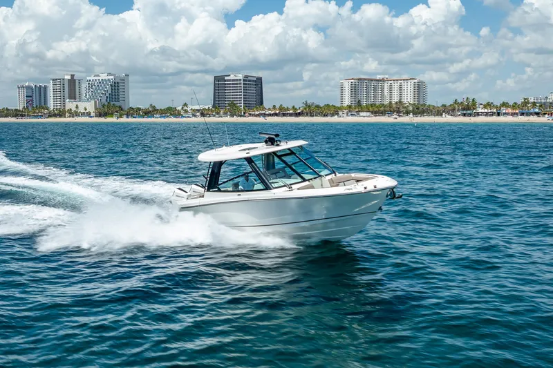Slide: The Image of 2025 Boston Whaler 330 Vantage cruising on ocean near city skyline. - 10