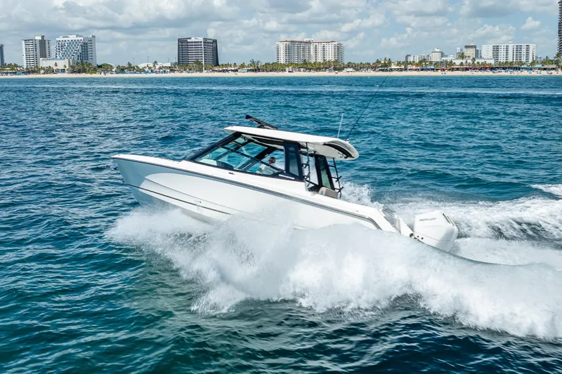 Slide: The Image of 2025 Boston Whaler 330 Vantage cruising on ocean near city skyline. - 11
