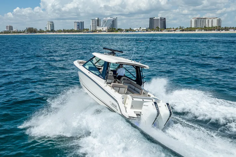 Slide: The Image of 2025 Boston Whaler 330 Vantage cruising on ocean near city skyline. - 12