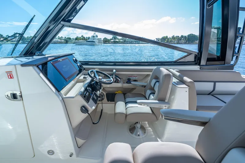 Slide: The Image of 2025 Boston Whaler 330 Vantage boat interior with modern helm and seating, overlooking serene waters. - 16