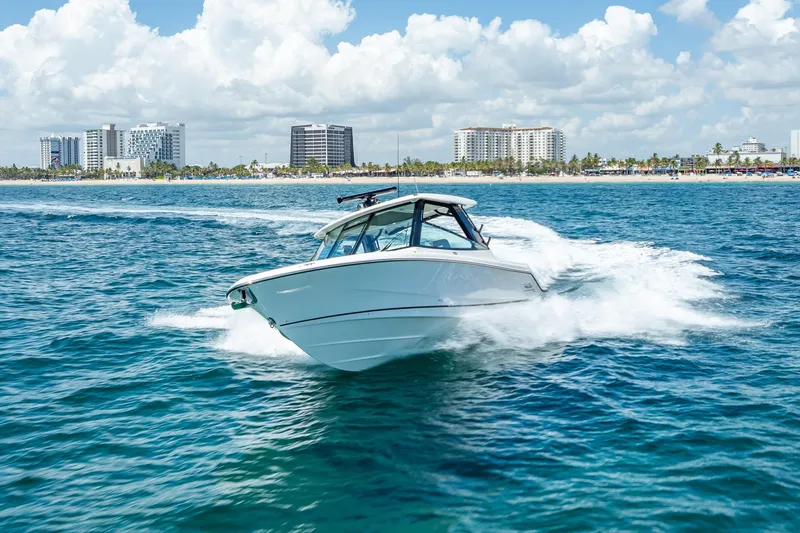 Slide: The Image of 2025 Boston Whaler 330 Vantage cruising on ocean near city skyline. - 2