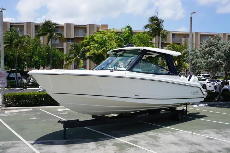 Slide: The Image of 2025 Boston Whaler 330 Vantage boat on trailer in sunny parking lot. - 22