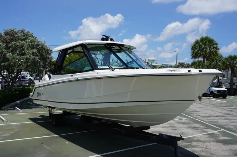 Slide: The Image of 2025 Boston Whaler 330 Vantage boat on trailer in sunny parking lot. - 27