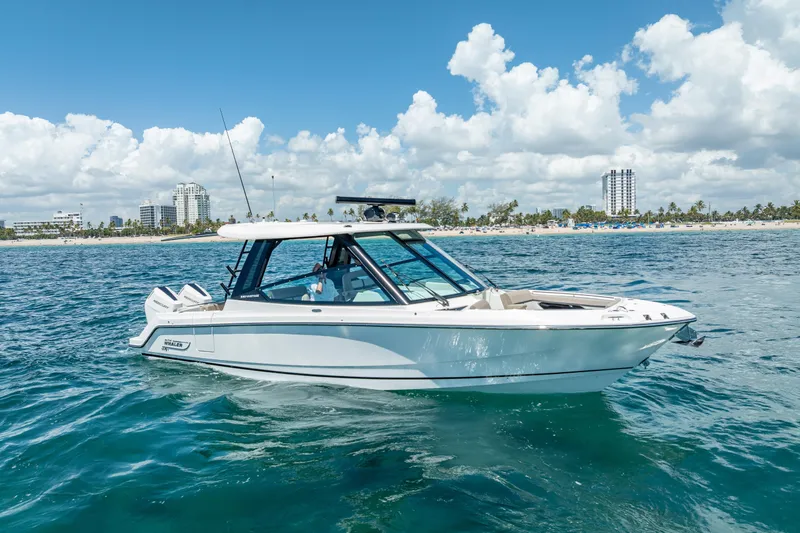 Slide: The Image of 2025 Boston Whaler 330 Vantage boat cruising on clear blue ocean near a sunny coastline. - 3