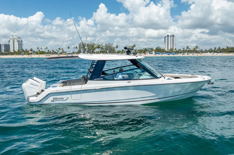 Slide: The Image of 2025 Boston Whaler 330 Vantage boat cruising on clear blue ocean near a sunny beach. - 4