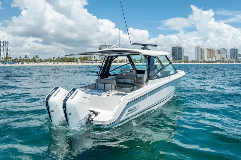 Slide: The Image of 2025 Boston Whaler 330 Vantage boat cruising near a city shoreline under a cloudy sky. - 5