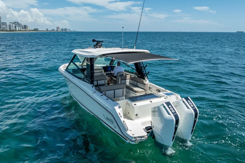 Slide: The Image of 2025 Boston Whaler 330 Vantage boat cruising on open ocean near city skyline. - 7