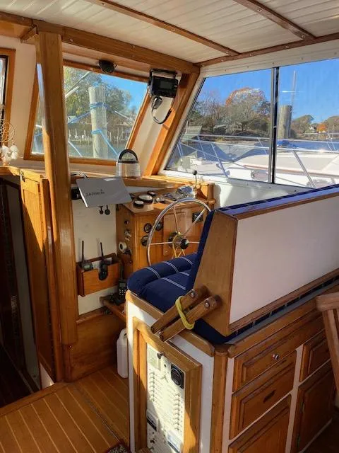 Slide: The Image of 1986 Wilbur 34 boat interior with wooden helm and blue cushioned seat. - 12
