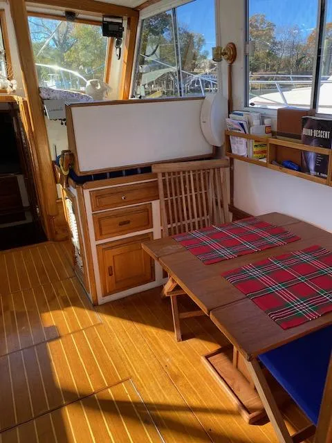 Slide: The Image of 1986 Wilbur 34 boat interior with wooden flooring, dining area, and large windows. - 13