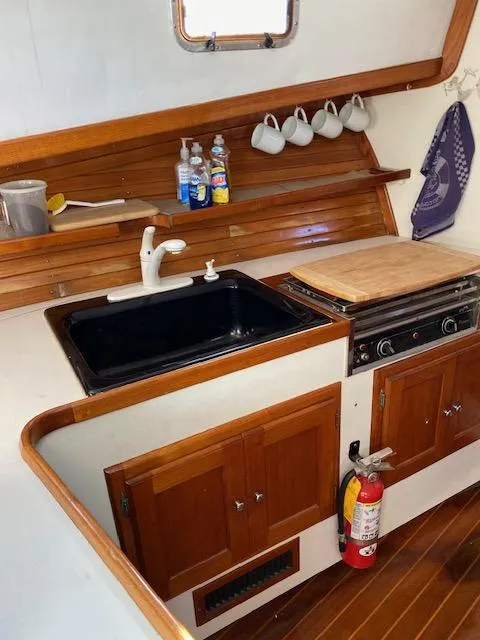 Slide: The Image of 1986 Wilbur 34 boat kitchen with wooden cabinets, sink, stove, and fire extinguisher. - 19