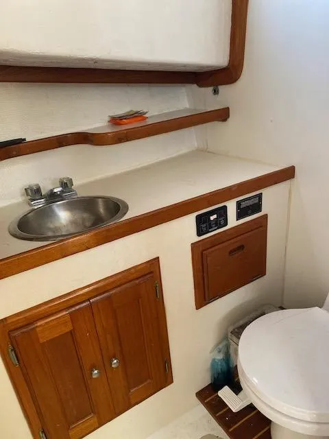 Slide: The Image of 1986 Wilbur 34 boat bathroom with sink, wooden cabinets, and toilet. - 22