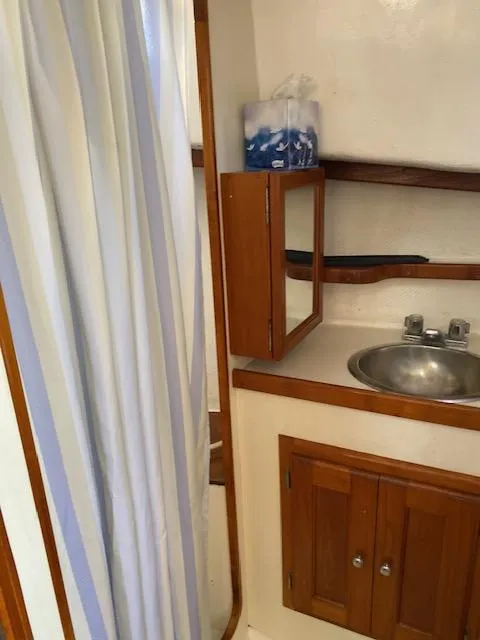 Slide: The Image of 1986 Wilbur 34 boat bathroom with sink, mirror, and shower curtain. - 23