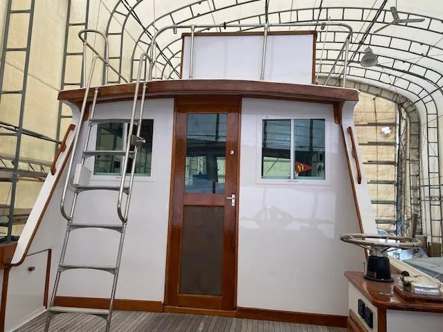 Slide: The Image of 1986 Wilbur 34 boat cabin with wooden accents and metal ladder in covered storage. - 25