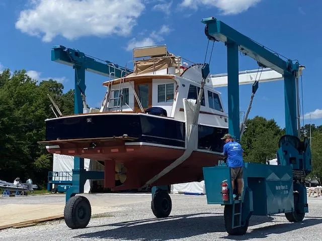 Slide: The Image of 1986 Wilbur 34 boat on a lift, clear sky, maintenance work in progress. - 26