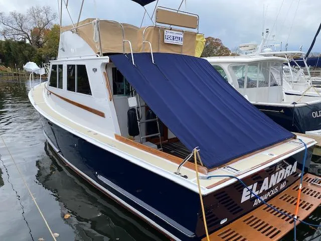 Slide: The Image of 1986 Wilbur 34 boat with blue cover, docked, for sale sign visible. - 3