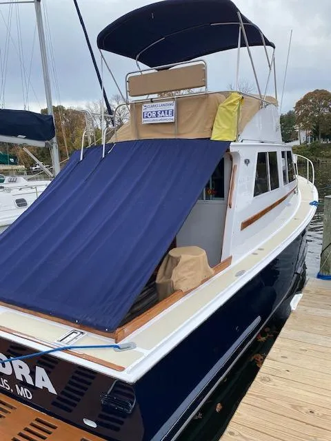 Slide: The Image of 1986 Wilbur 34 boat for sale, docked with blue cover and canopy. - 5