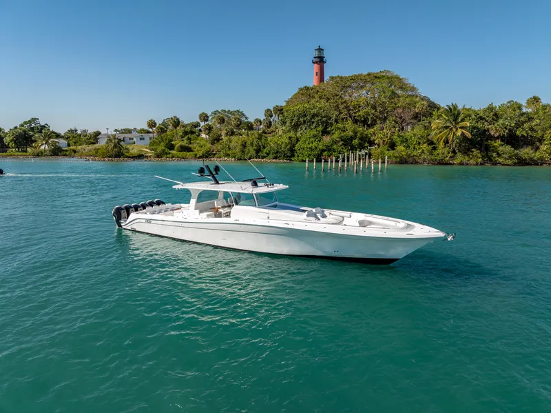 Slide: The Image of 2025 HCB 65 Estrella boat on turquoise water near lush island and lighthouse. - 3