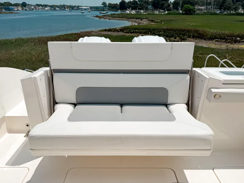 Slide: The Image of 2022 Pursuit S 328 Sport boat with cushioned seating, overlooking serene waterfront scenery. - 10