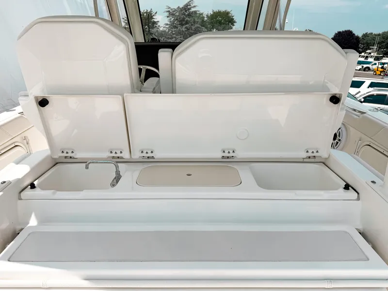 Slide: The Image of 2022 Pursuit S 328 Sport boat interior with open storage compartments and sink. - 15