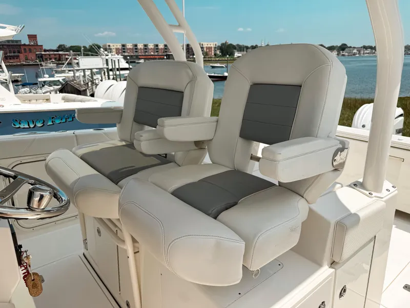 Slide: The Image of 2022 Pursuit S 328 Sport boat seats with armrests, docked by waterfront. - 20