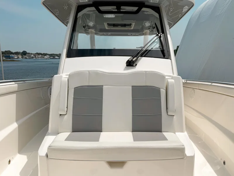 Slide: The Image of 2022 Pursuit S 328 Sport boat with cushioned seating, docked by the water. - 25