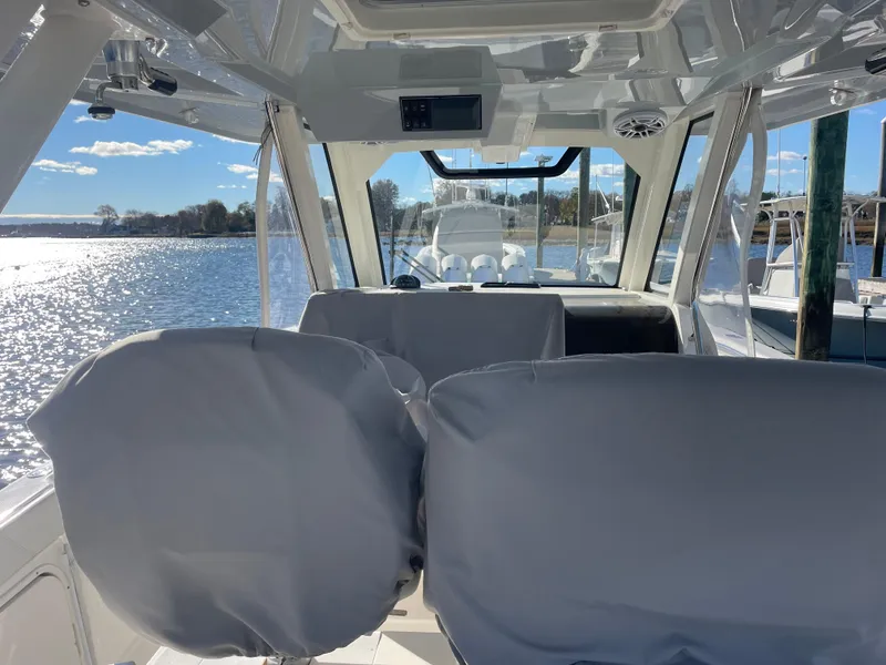 Slide: The Image of Interior view of 2022 Pursuit S328 boat with covered seats, overlooking a sunny waterfront. - 38