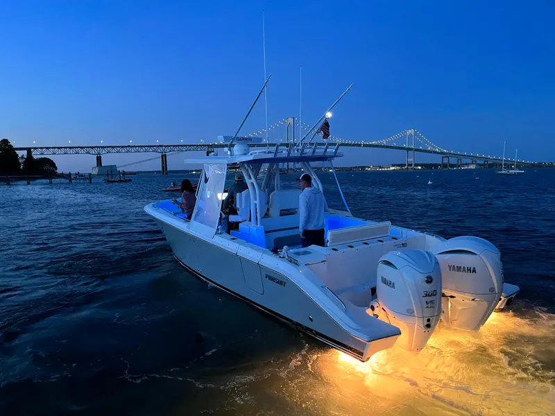 Slide: The Image of 2022 Pursuit S328 boat illuminated at dusk near a bridge. - 44