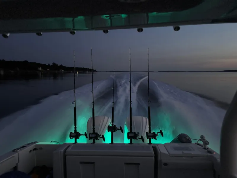 Slide: The Image of Pursuit S328 boat at dusk with fishing rods and glowing wake. - 45