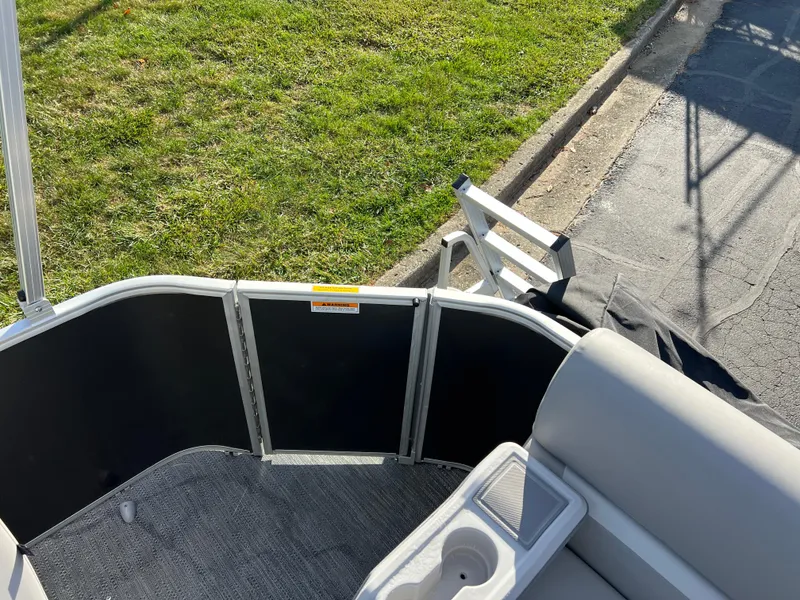 Slide: The Image of 2025 Godfrey Xperience 1880 CX boat interior with seating and cup holder, parked on grass. - 13