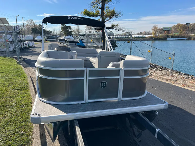 Slide: The Image of 2025 Godfrey Xperience 1880 CX pontoon boat docked by a scenic waterfront. - 2