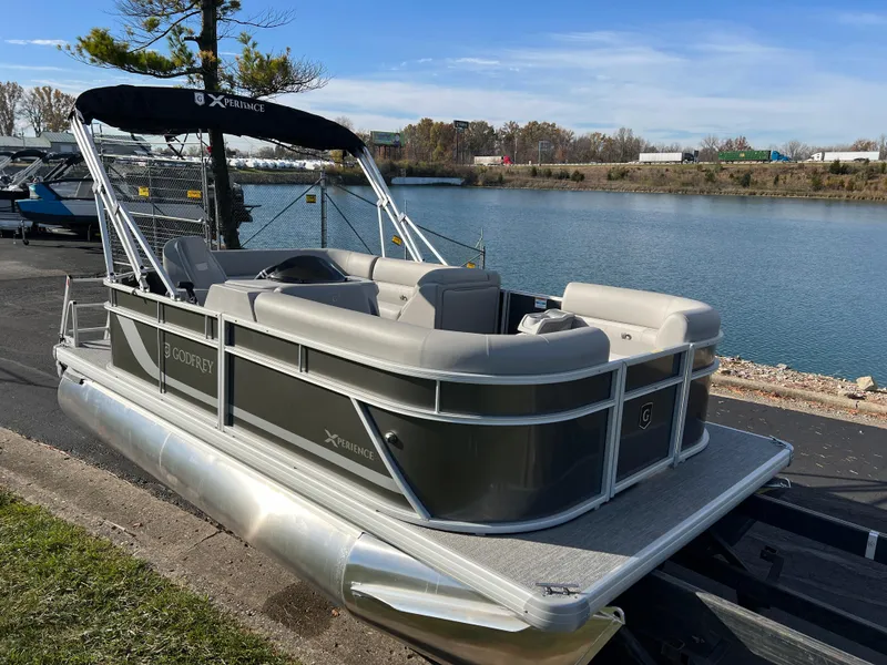 Slide: The Image of 2025 Godfrey Xperience 1880 CX pontoon boat docked by a serene lake. - 3