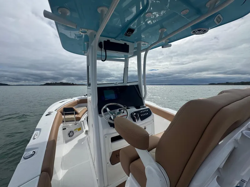 Slide: The Image of 2025 NauticStar 242OS boat interior with helm, tan seating, and ocean view. - 16