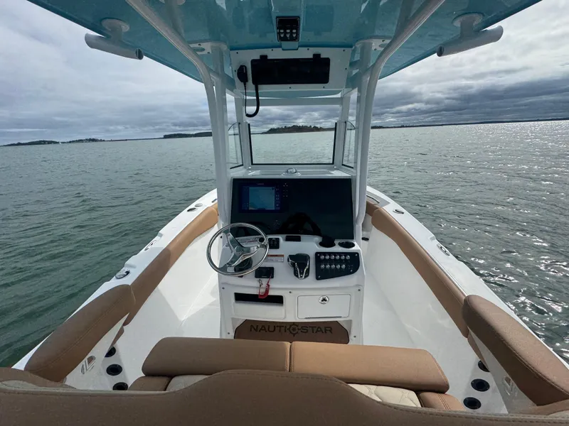 Slide: The Image of 2025 NauticStar 242OS boat interior with steering console on calm water. - 17