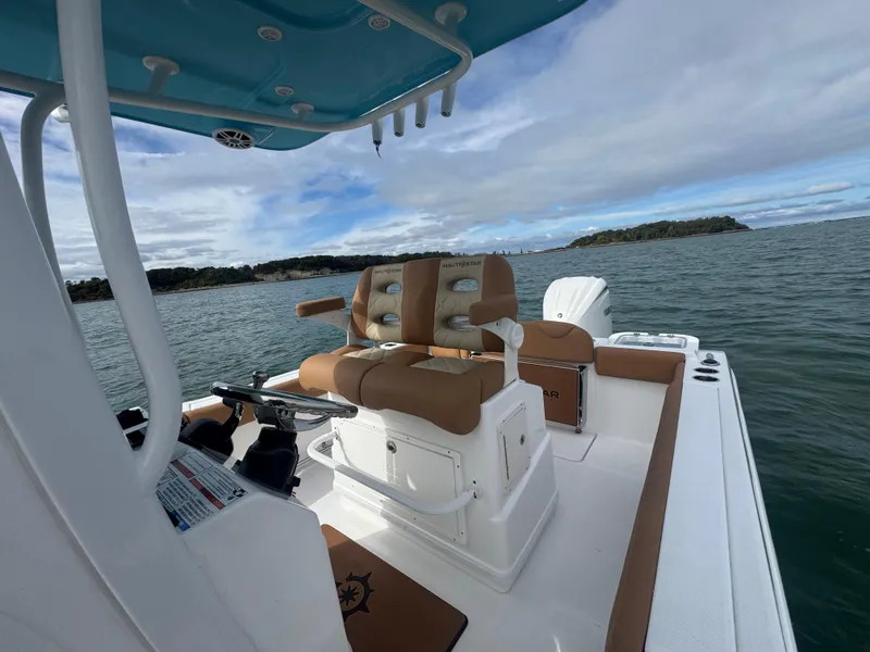 Slide: The Image of 2025 NauticStar 242OS boat interior with helm and seating on open water. - 18