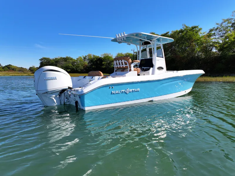 Slide: The Image of 2025 NauticStar 242OS boat on calm water, featuring a sleek blue and white design. - 6