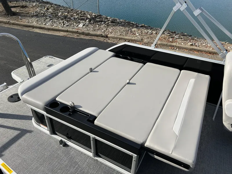 Slide: The Image of 2025 Godfrey XPERIENCE 2286 SFLC boat with cushioned seating near water. - 14