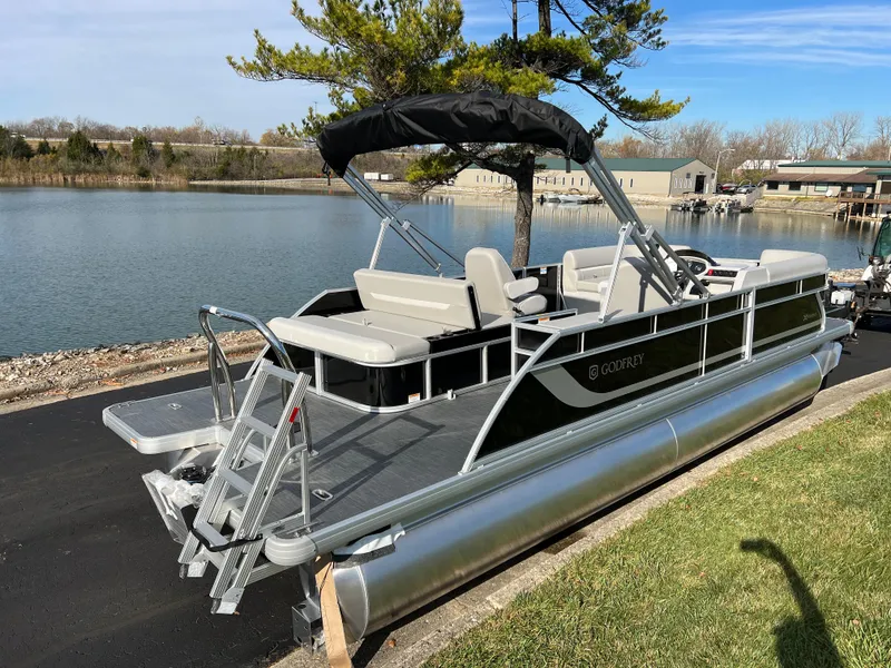 Slide: The Image of 2025 Godfrey XPERIENCE 2286 SFLC pontoon boat docked by a serene lake. - 4