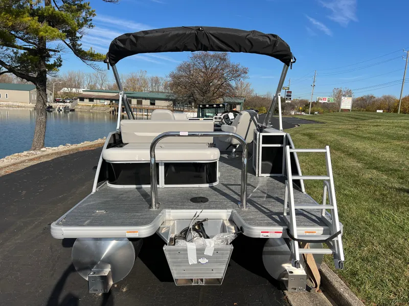 Slide: The Image of 2025 Godfrey XPERIENCE 2286 SFLC pontoon boat with canopy, docked by a lakeside road. - 5