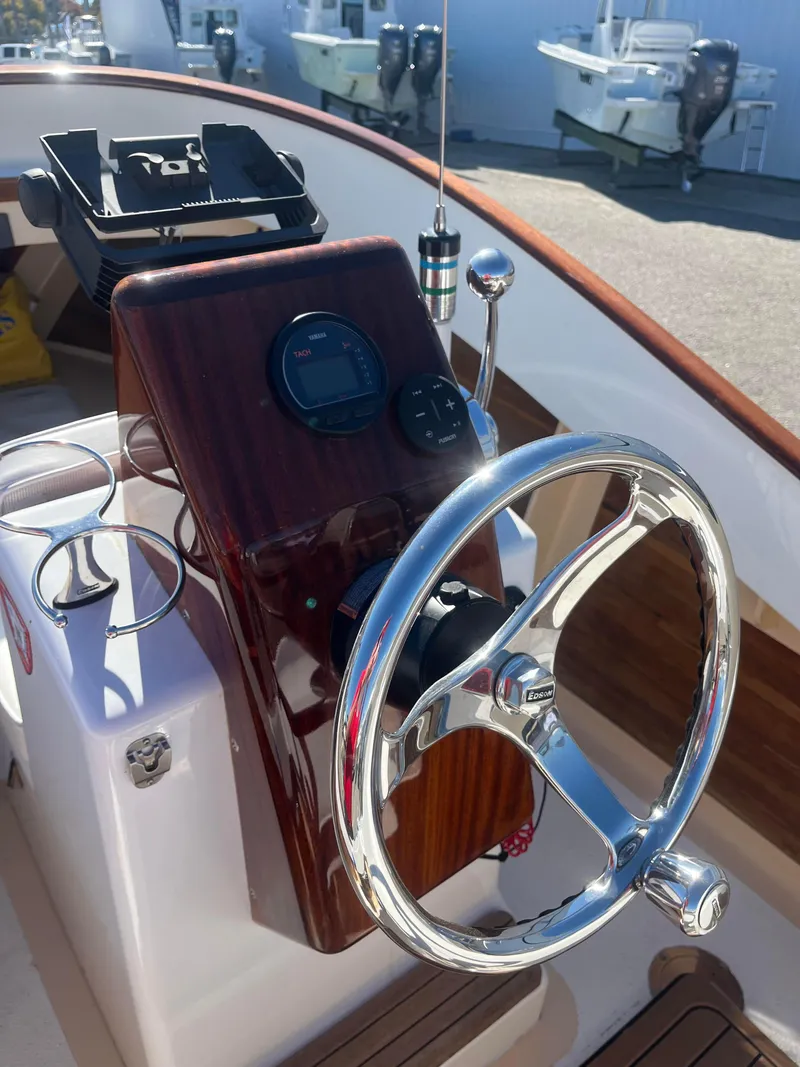 Slide: The Image of Steering console of 2013 Quiet Waters Boatworks Hill 16 with chrome wheel and wooden panel. - 4