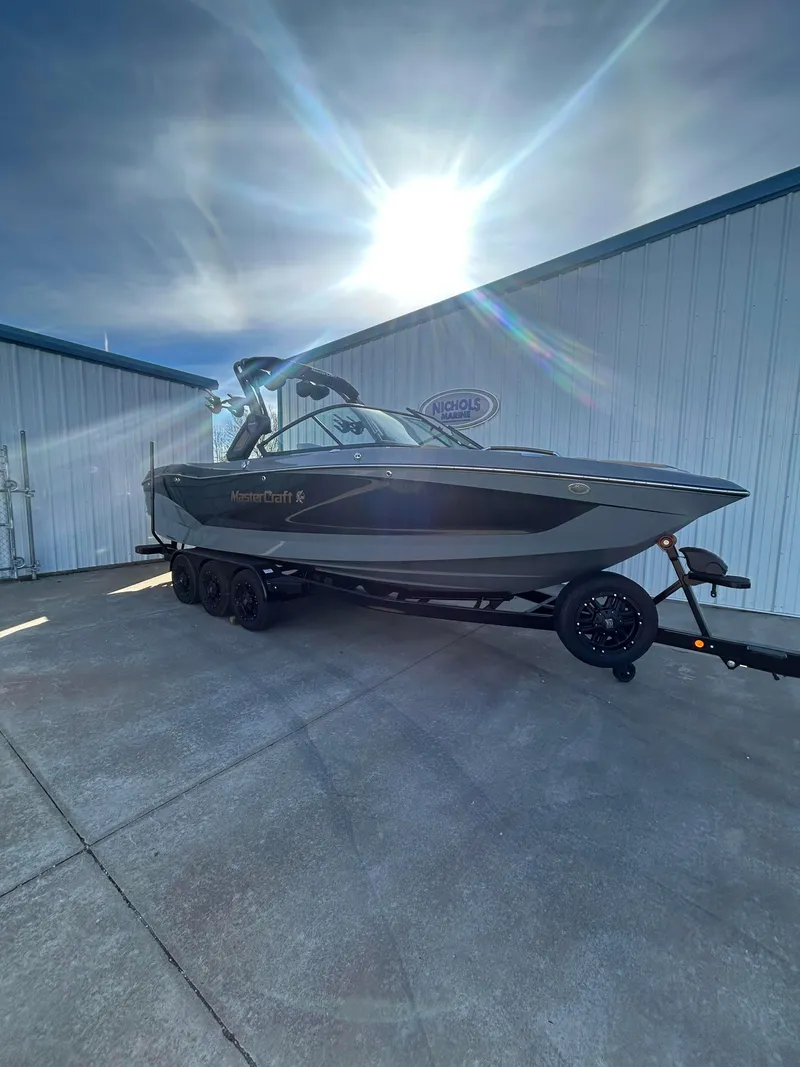 Slide: The Image of 2025 MasterCraft X26 boat on trailer under bright sun. - 3