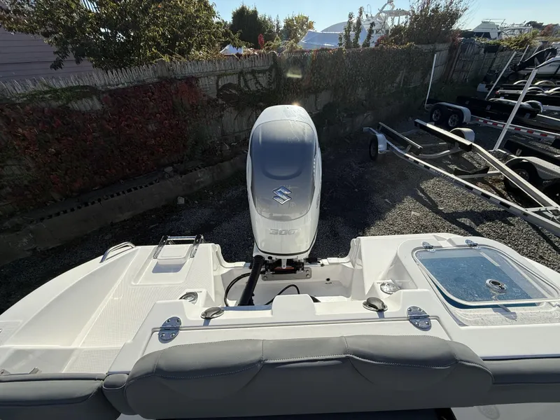 Slide: The Image of 2025 NauticStar 242OS boat with Suzuki outboard motor in a yard setting. - 10
