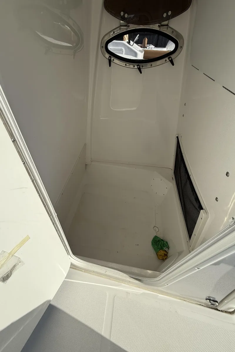 Slide: The Image of 2025 NauticStar 242OS boat interior cabin with porthole and storage space. - 14