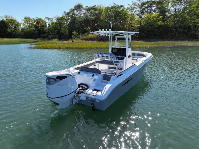 Slide: The Image of 2025 NauticStar 242OS boat on calm water, surrounded by lush greenery. - 2