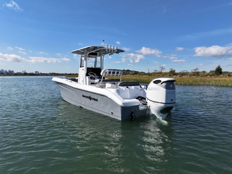 Slide: The Image of 2025 NauticStar 242OS boat on calm water under clear blue sky. - 4