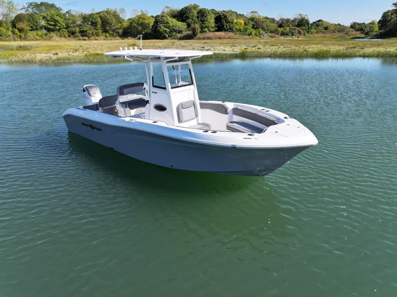 Slide: The Image of 2025 NauticStar 242OS boat on calm water, surrounded by lush greenery. - 7