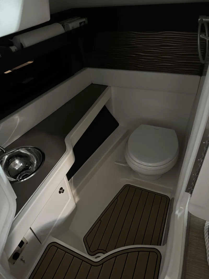 Slide: The Image of 2020 Sea Ray 310SLX boat bathroom with sink, toilet, and wooden floor mats. - 5