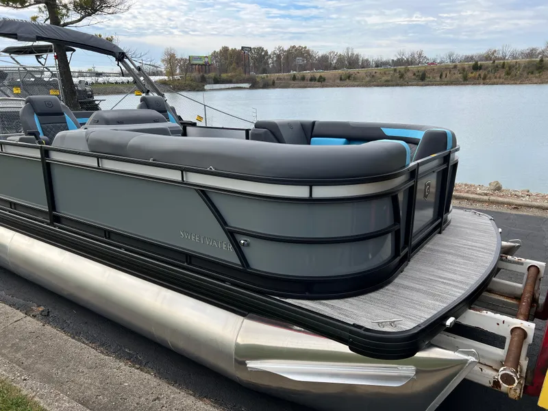Slide: The Image of 2025 Godfrey Sweetwater 2286 sFLC TRI PWR STR pontoon boat docked by a serene lake. - 2